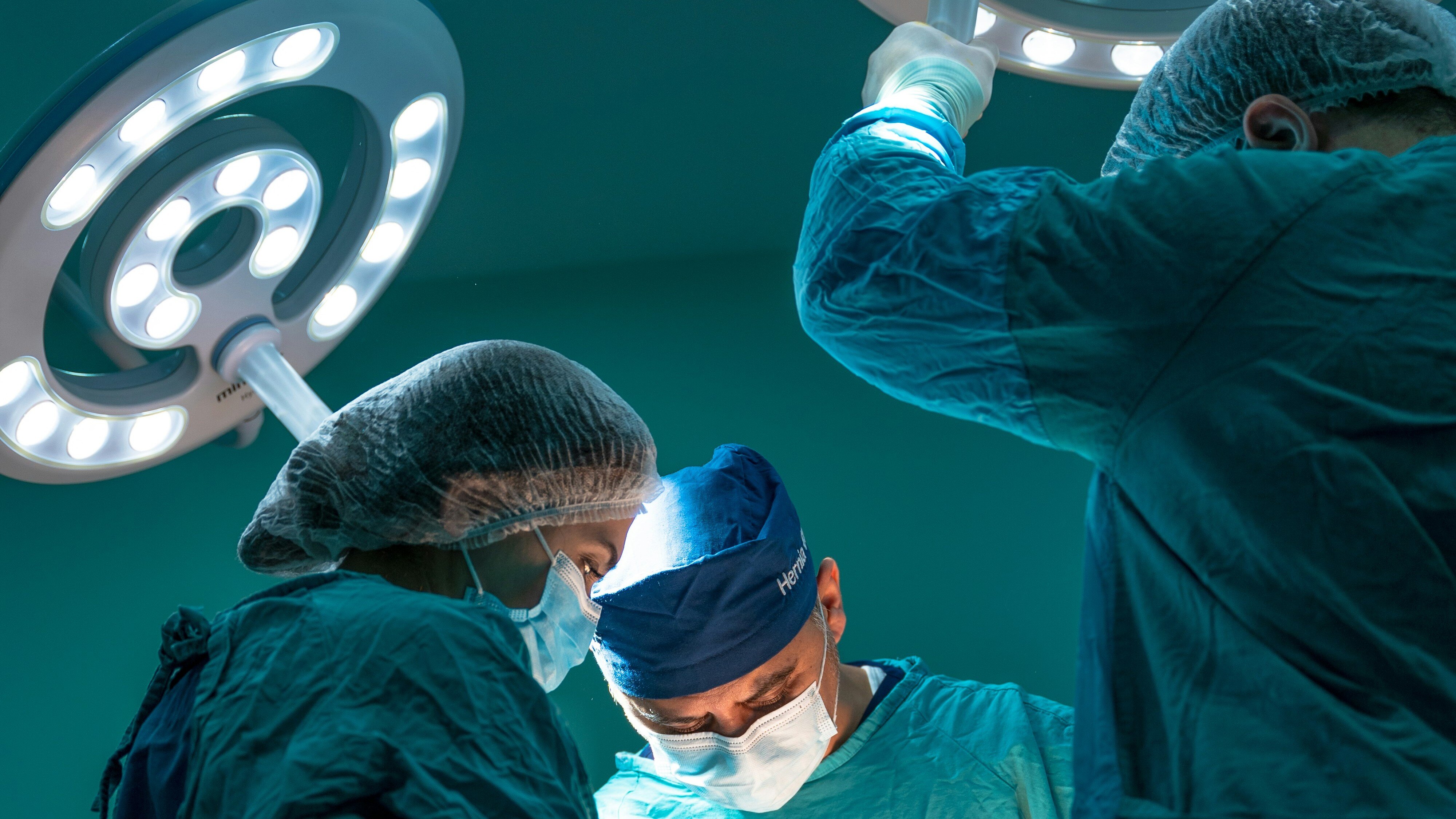 Surgeons in operating room with laminar flow surgical lights above